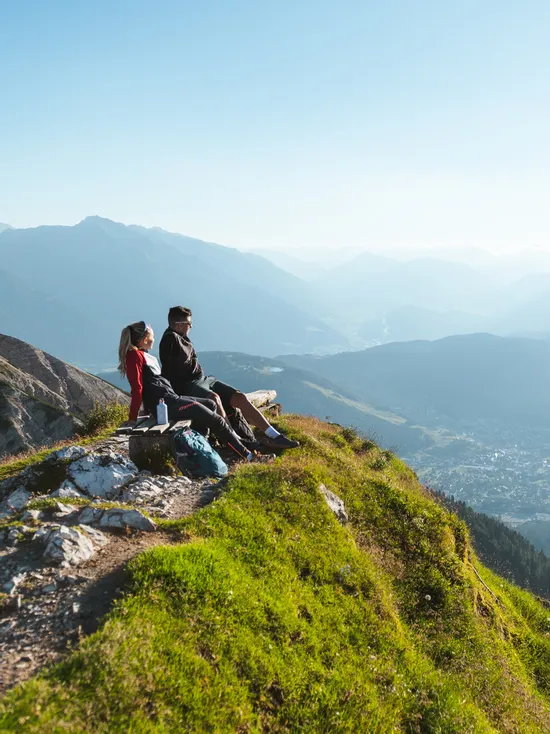 Wanderer entspannen auf Bank mit Blick auf alpines Tal und Berglandschaft